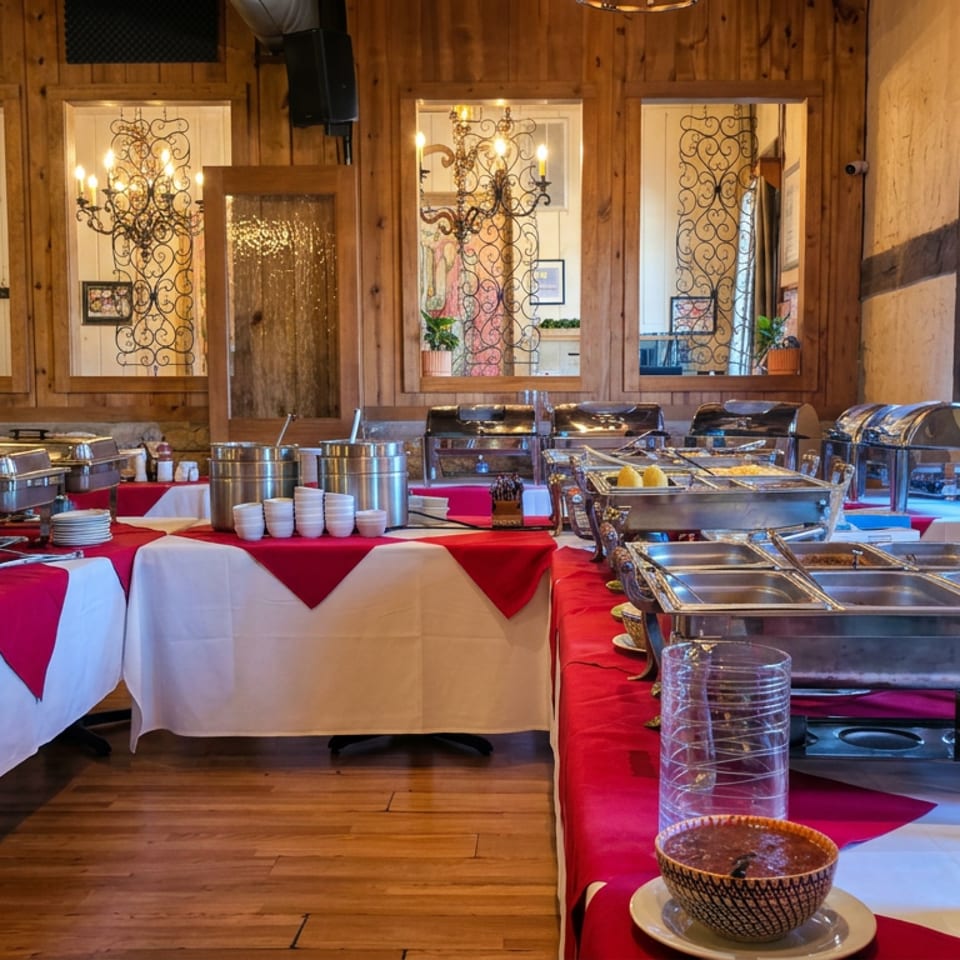 Restaurant dining room with red-and-white buffet tables, stainless-steel serving trays, bowls, and rustic wood-and-stone décor.