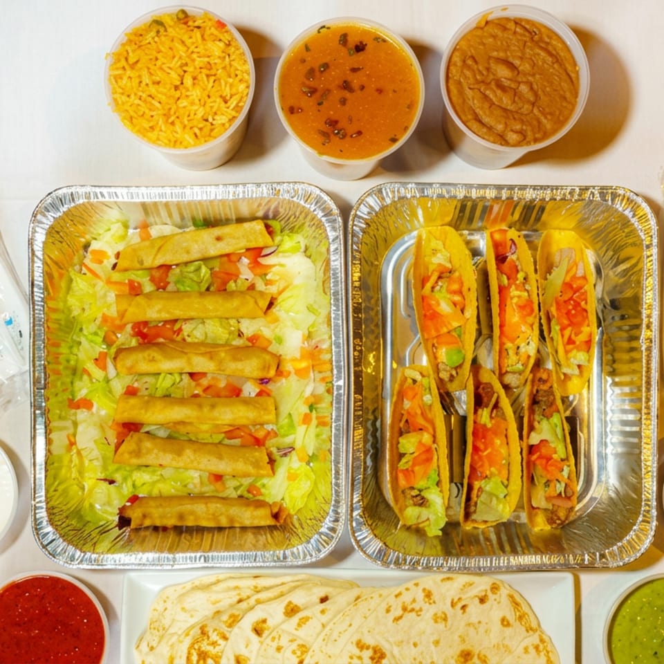 Overhead spread of tacos, fried rolls over salad, rice, curry, beans, flatbreads, and assorted sauces in takeaway containers.